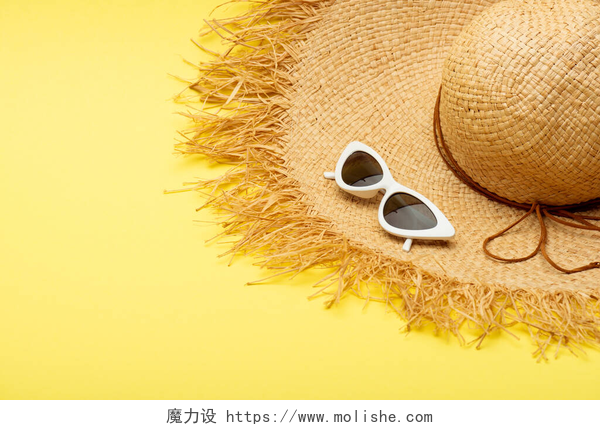 黄色背景上的草帽和太阳镜带黄色背景的草帽和时髦太阳镜